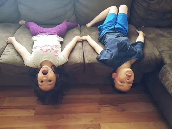 two kids hanging upside down on the sofa