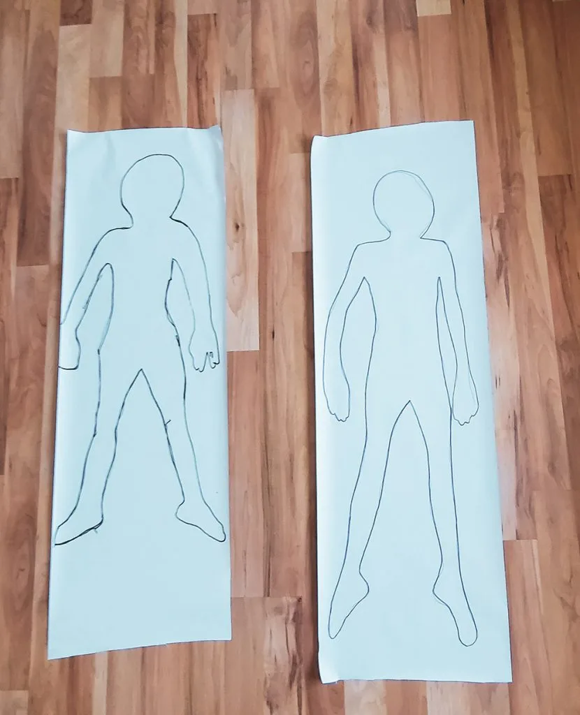 outline of kids bodies on paper for body check chart.