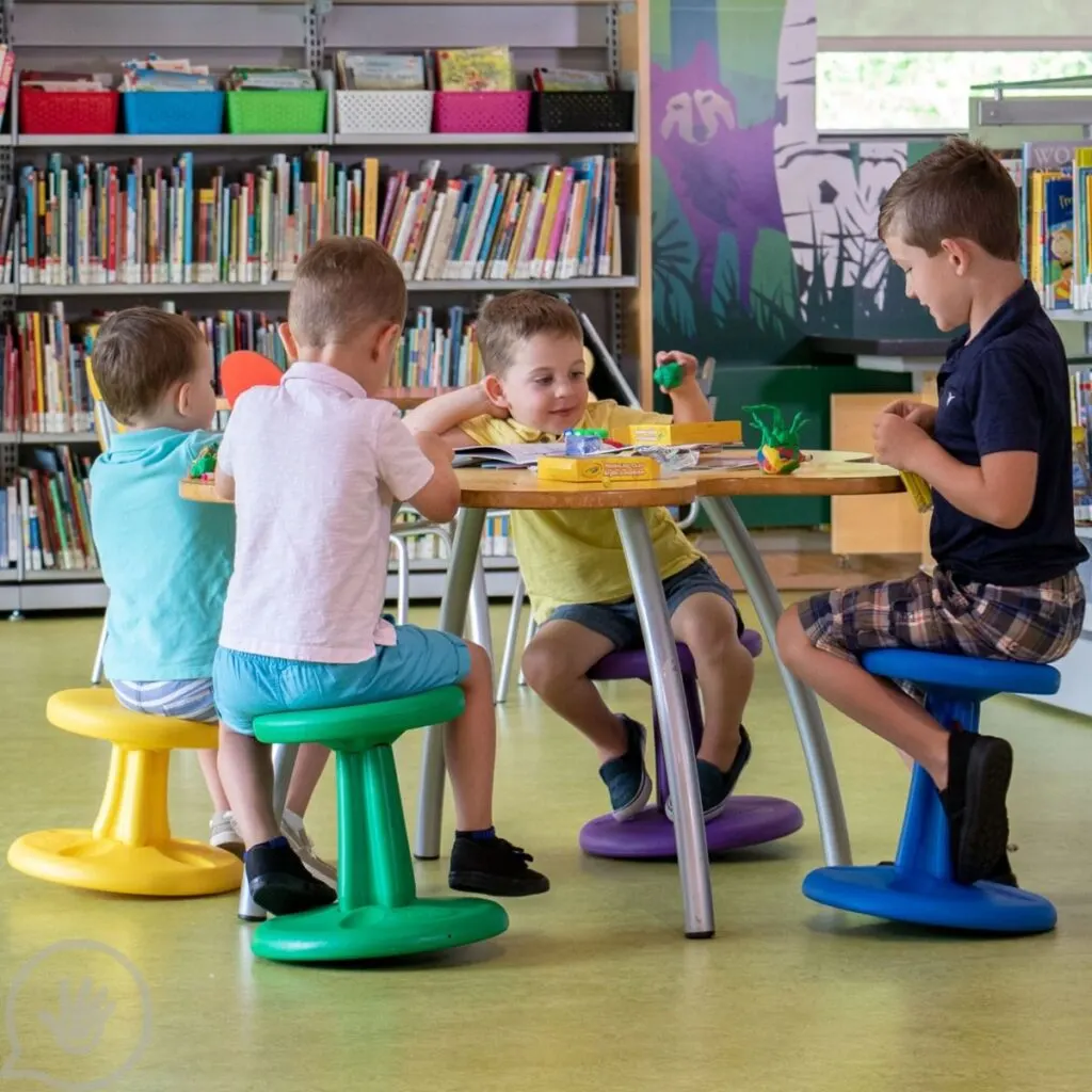 Imagine of children using wobble chairs, alternative seating is a key part of developing a sensory-friendly classroom.